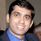 A man in a suit and tie smiling for the camera.