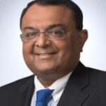 A man in a suit and tie smiling for the camera.