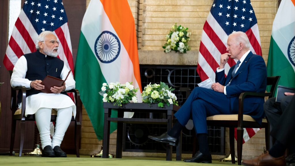 A man sitting next to an indian flag.