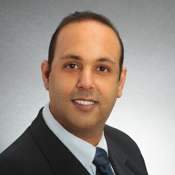 A man in a suit and tie smiling for the camera.