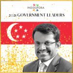 A man in glasses and suit standing next to an asian flag.