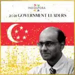 A man in glasses and tie standing next to an asian flag.