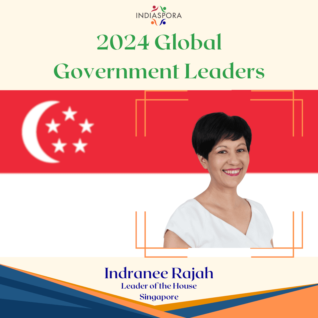 A picture of an asian woman with the flag of singapore.|A woman in red shirt and neck scarf talking to people.