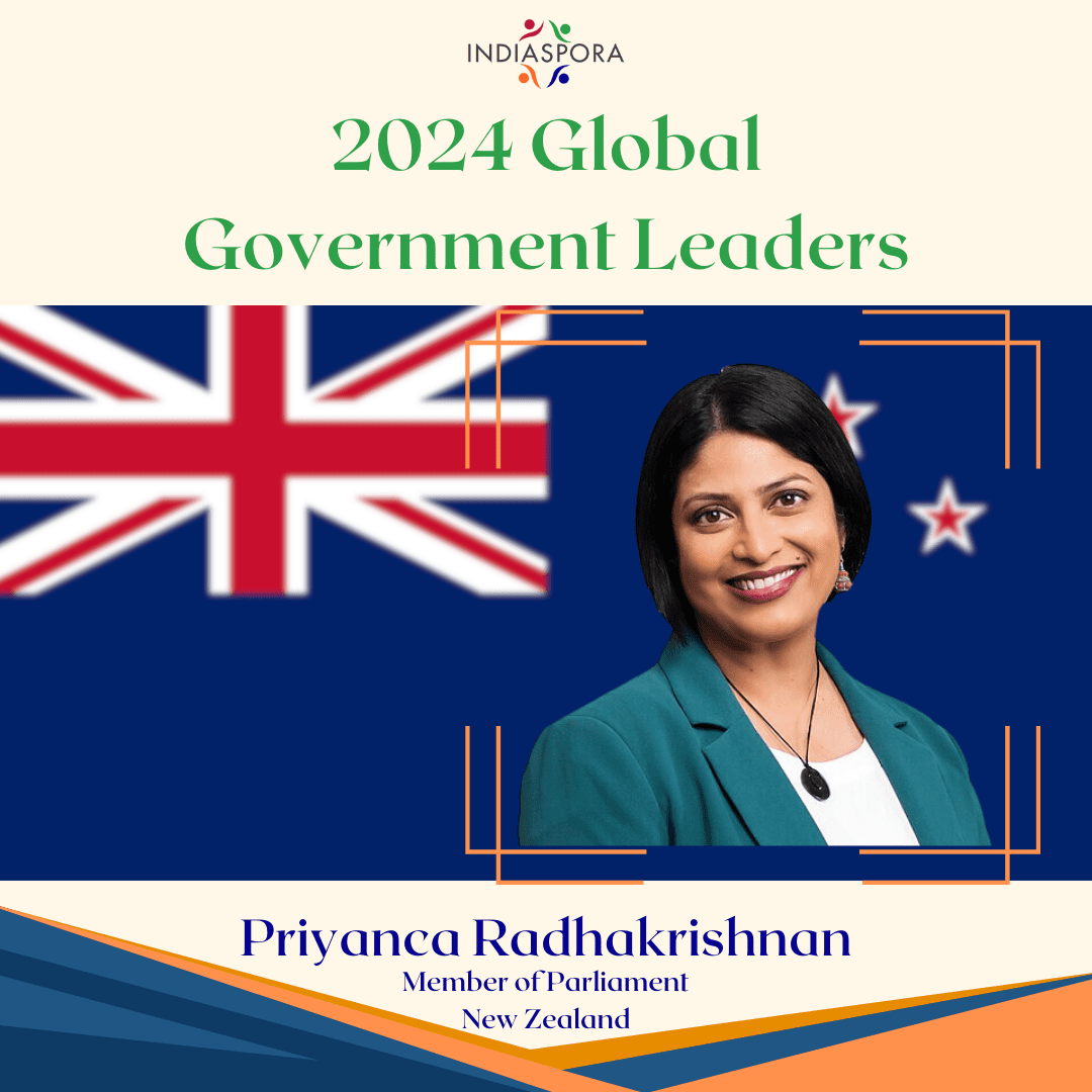 A woman standing in front of the flag of new zealand.|A woman in a green jacket smiling for the camera.