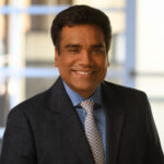 A man in a suit and tie smiling for the camera.