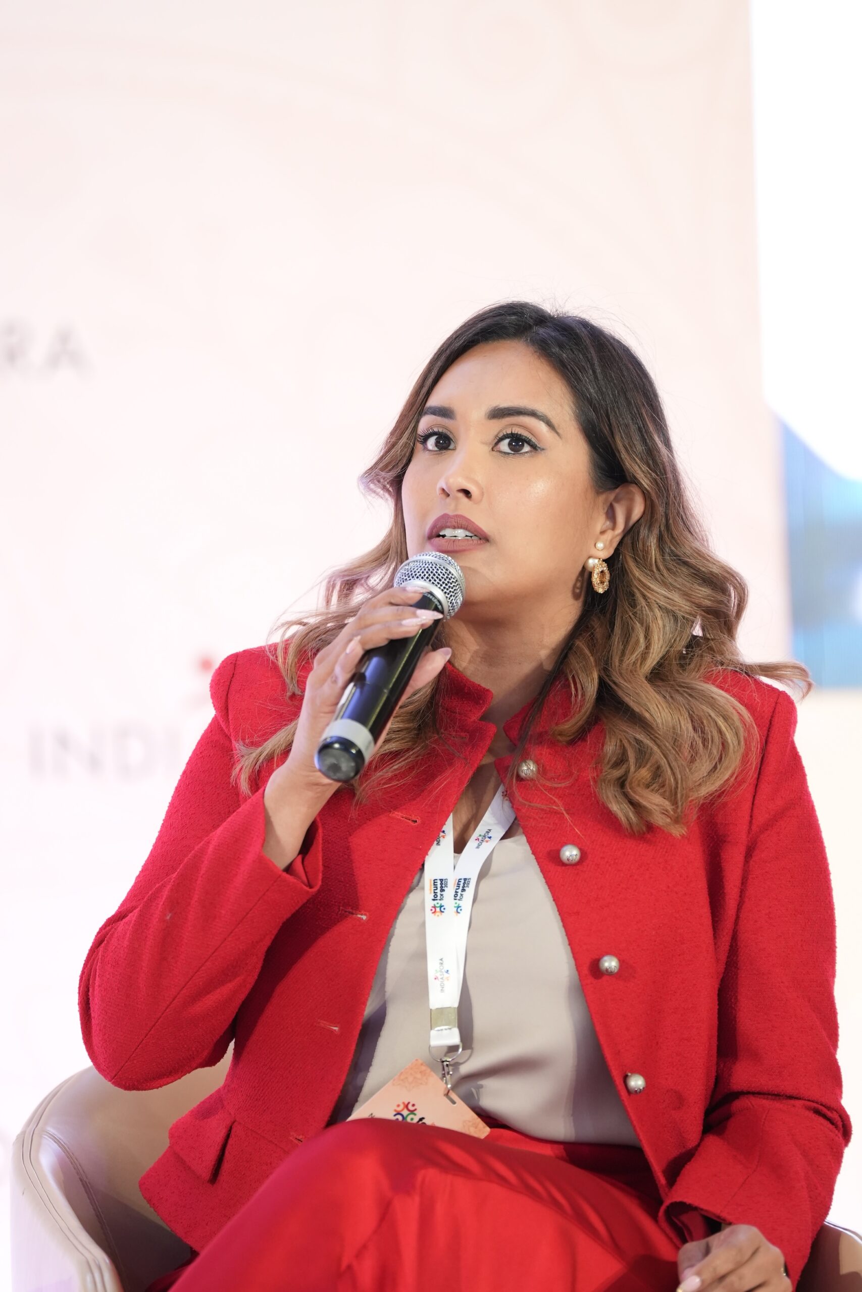 A woman in red jacket holding a microphone.