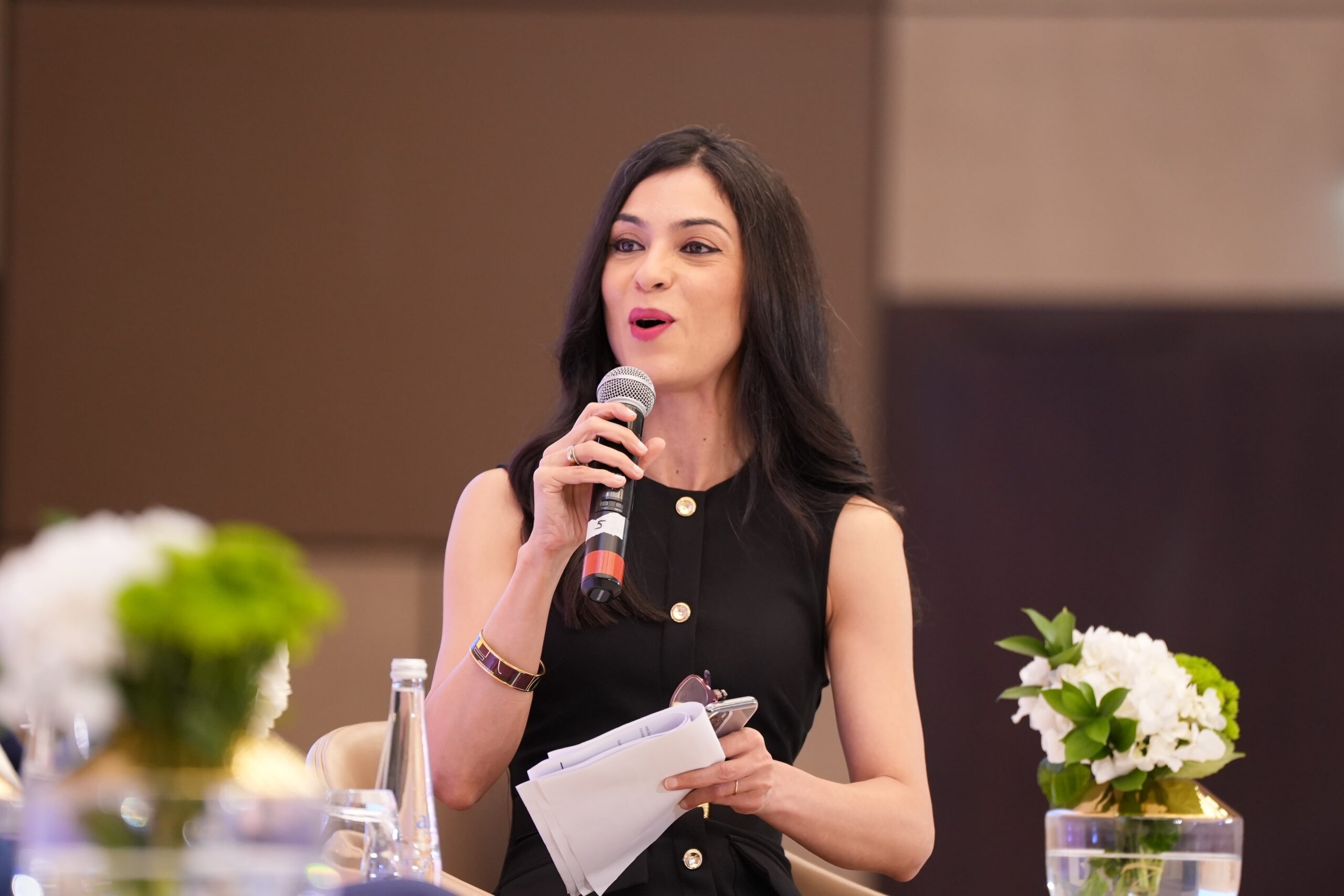 A woman is speaking at an event with papers.