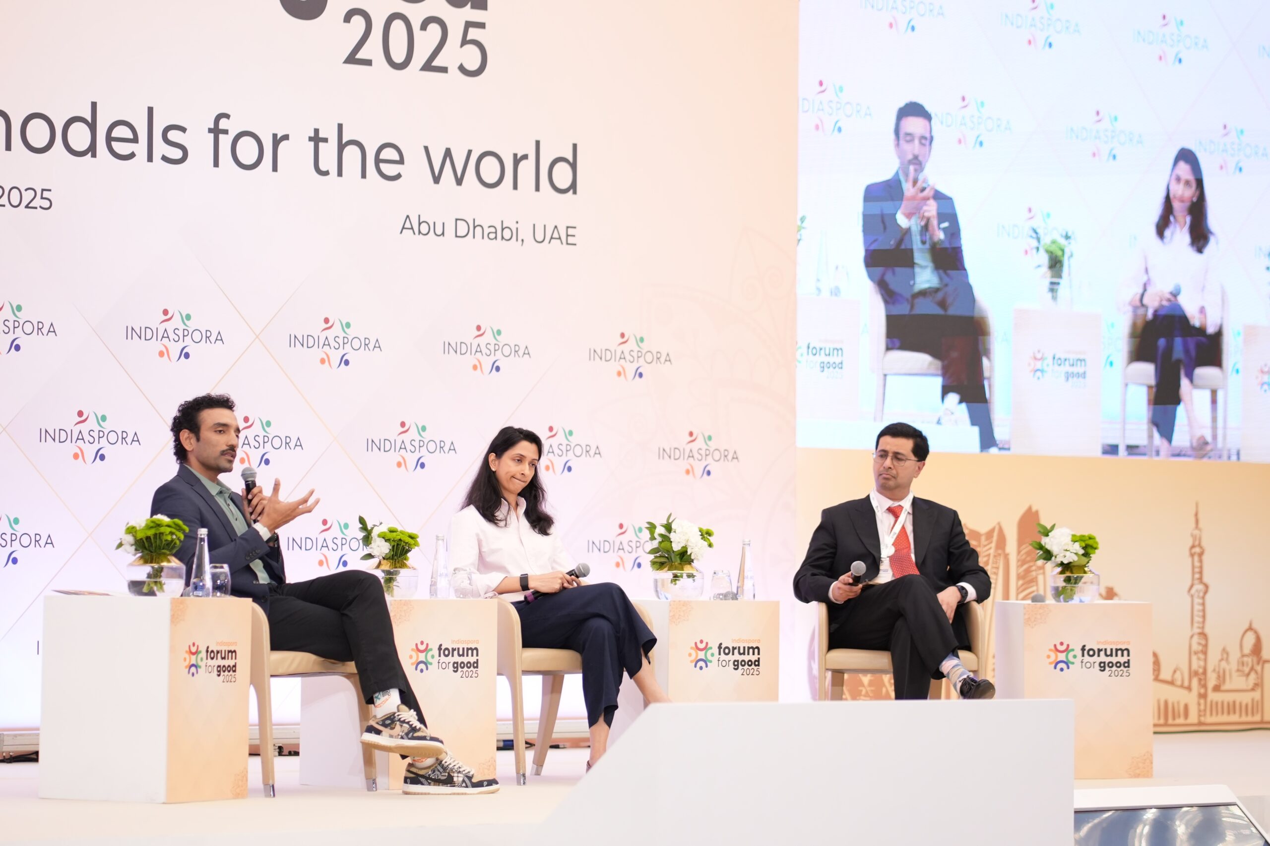 Three people sitting on chairs in front of a screen.