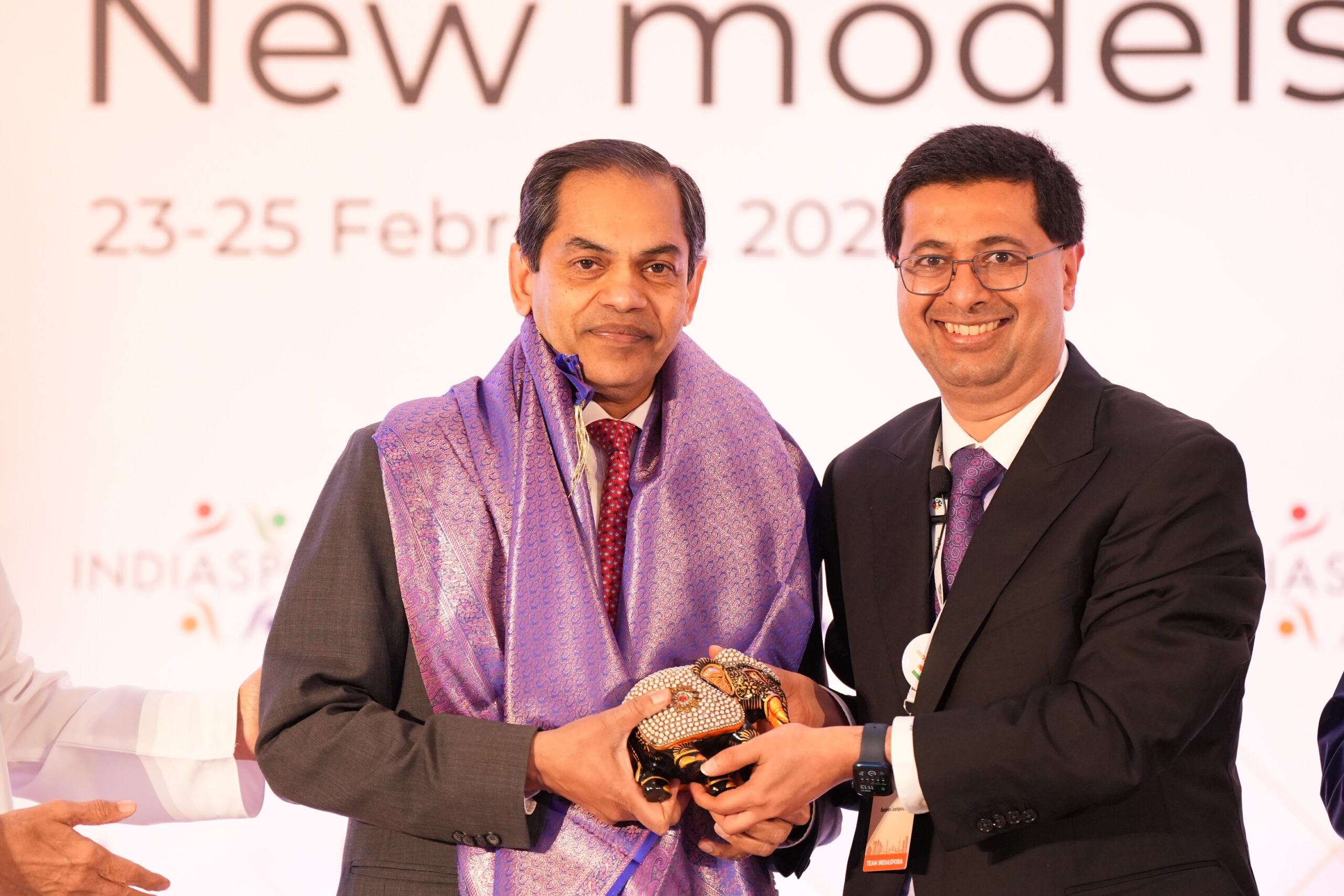 Two men in suits and ties holding a brown object.