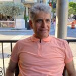 A man with grey hair sitting on top of a bench.