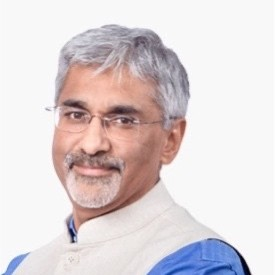 A man with grey hair and glasses is smiling.