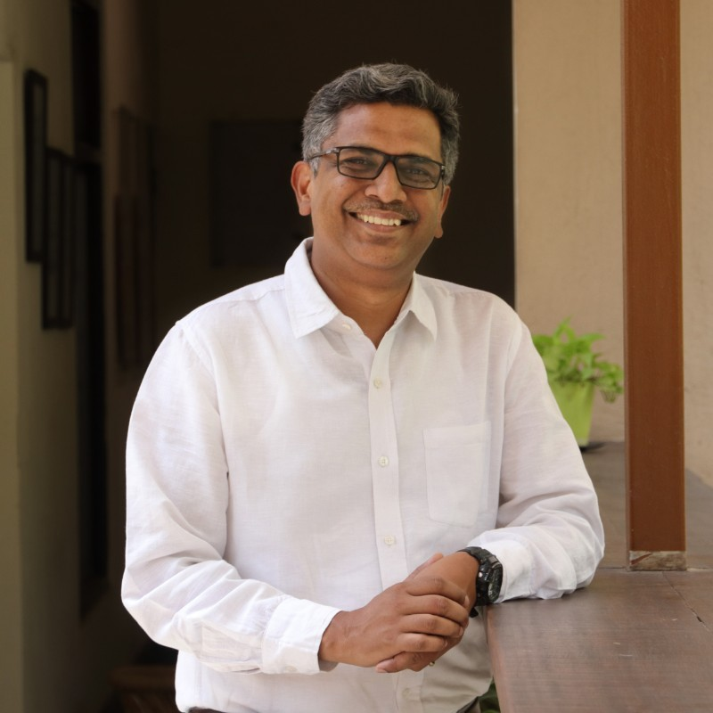 A man in white shirt and glasses standing next to a table.