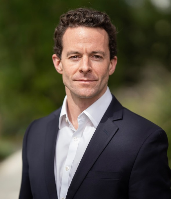 A man in a suit and tie standing outside.