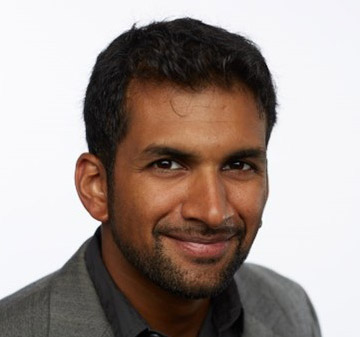 A man with a beard and suit jacket on.