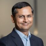 Smiling man in suit with blurred background.