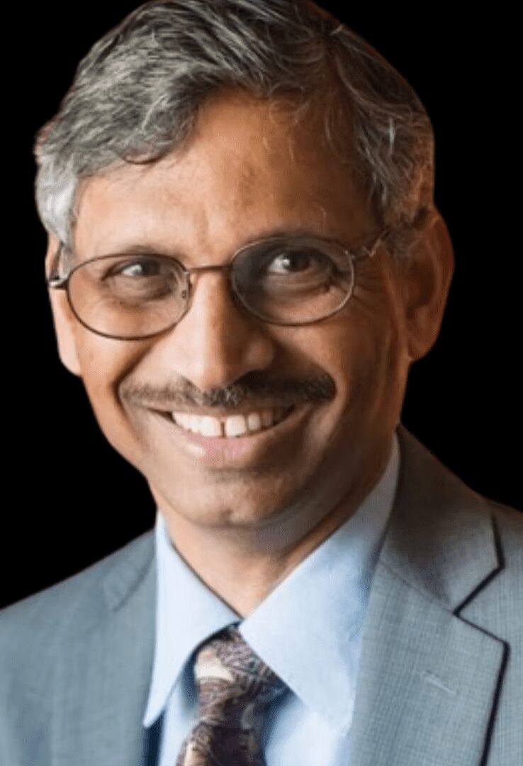 Smiling man in suit and glasses.