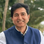 Smiling man outdoors in blue vest.