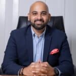 Smiling professional in navy suit at desk