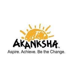 A yellow sun with the word akanksha underneath it.|A group of people standing in front of a wall.|A woman with long black hair wearing a white polka dot shirt.|A woman in a black jacket and pink scarf.|A woman with long hair wearing a black jacket.|A woman with long hair and wearing a black shirt.