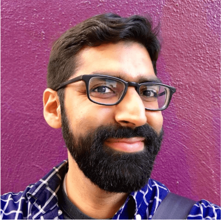 A man with glasses and beard standing in front of a purple wall.|A man with glasses and beard standing in front of a purple wall.|A black and white photo of a man with glasses.|A woman with a veil on her head.|A woman with long black hair wearing a red shirt.