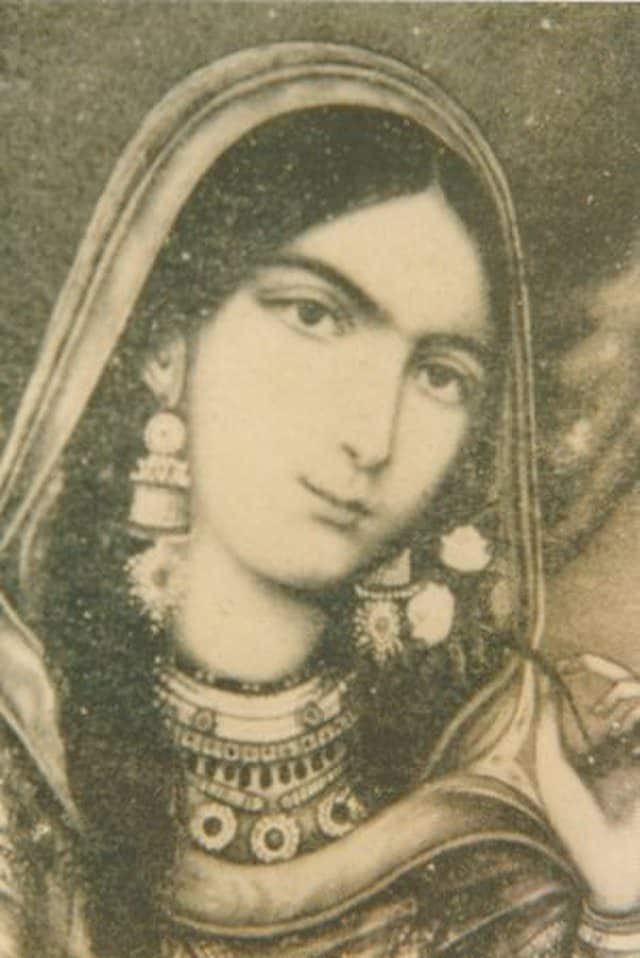 A woman with long hair and jewelry is shown.|A woman with dark hair and blue eyes smiling.