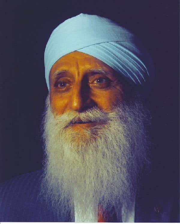 A man with long white beard and turban.|A man holding a rifle in front of a house.|A man and woman sitting on top of a couch.|A young man wearing glasses and a tan shirt.
