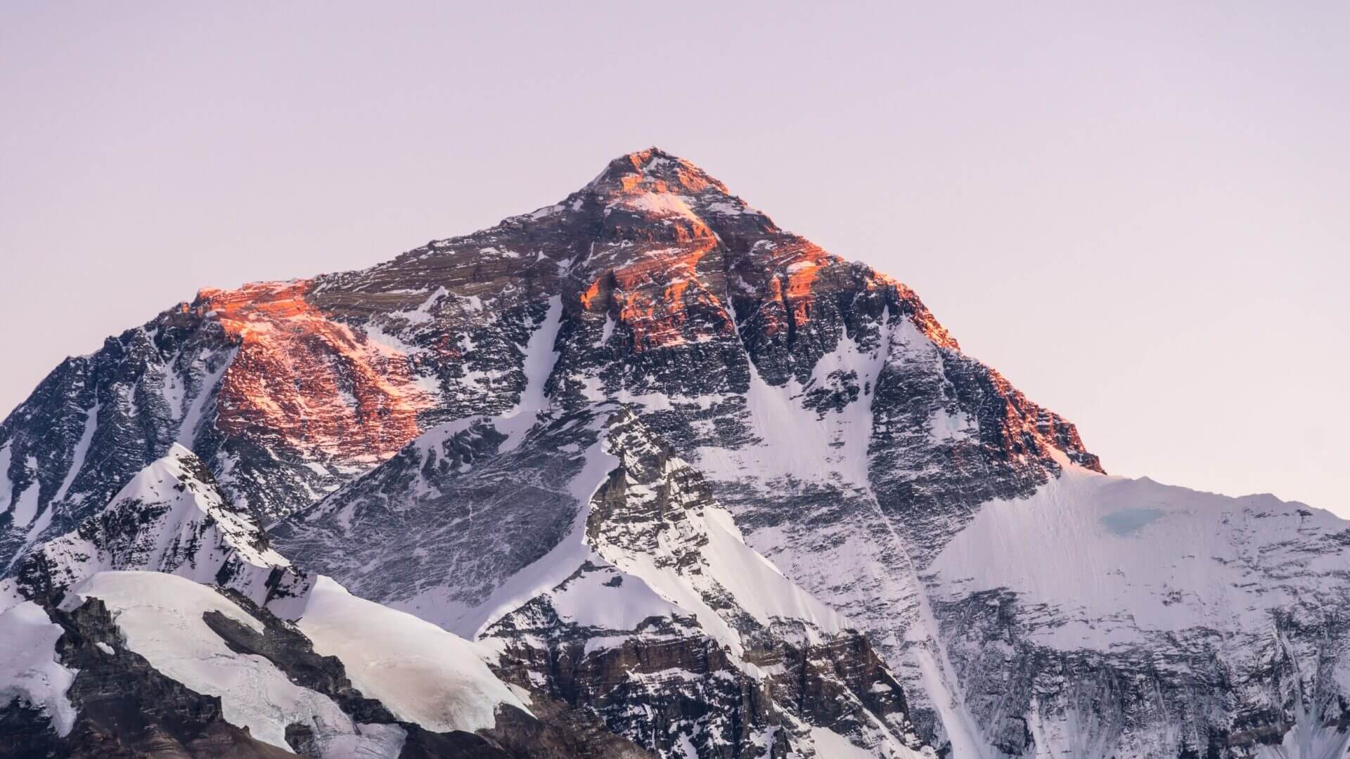 A mountain with snow on it's side and the sun shining|A book cover with mountains and trees in the background.