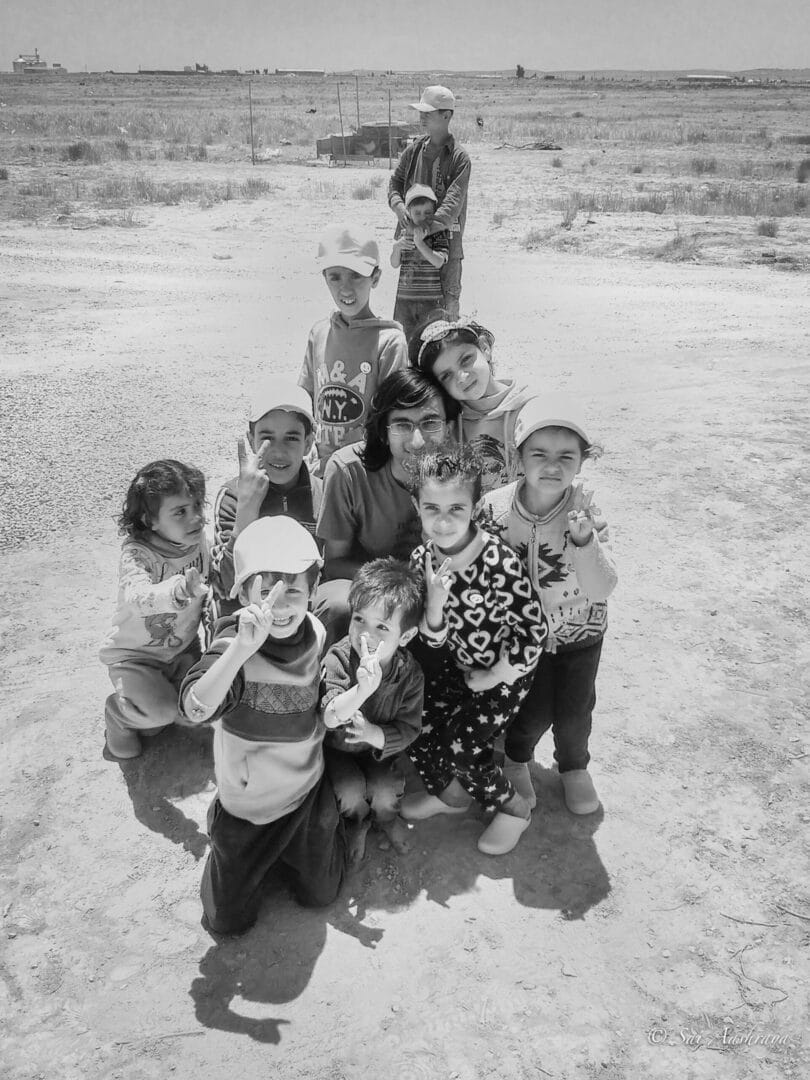 A group of children standing in the sand.