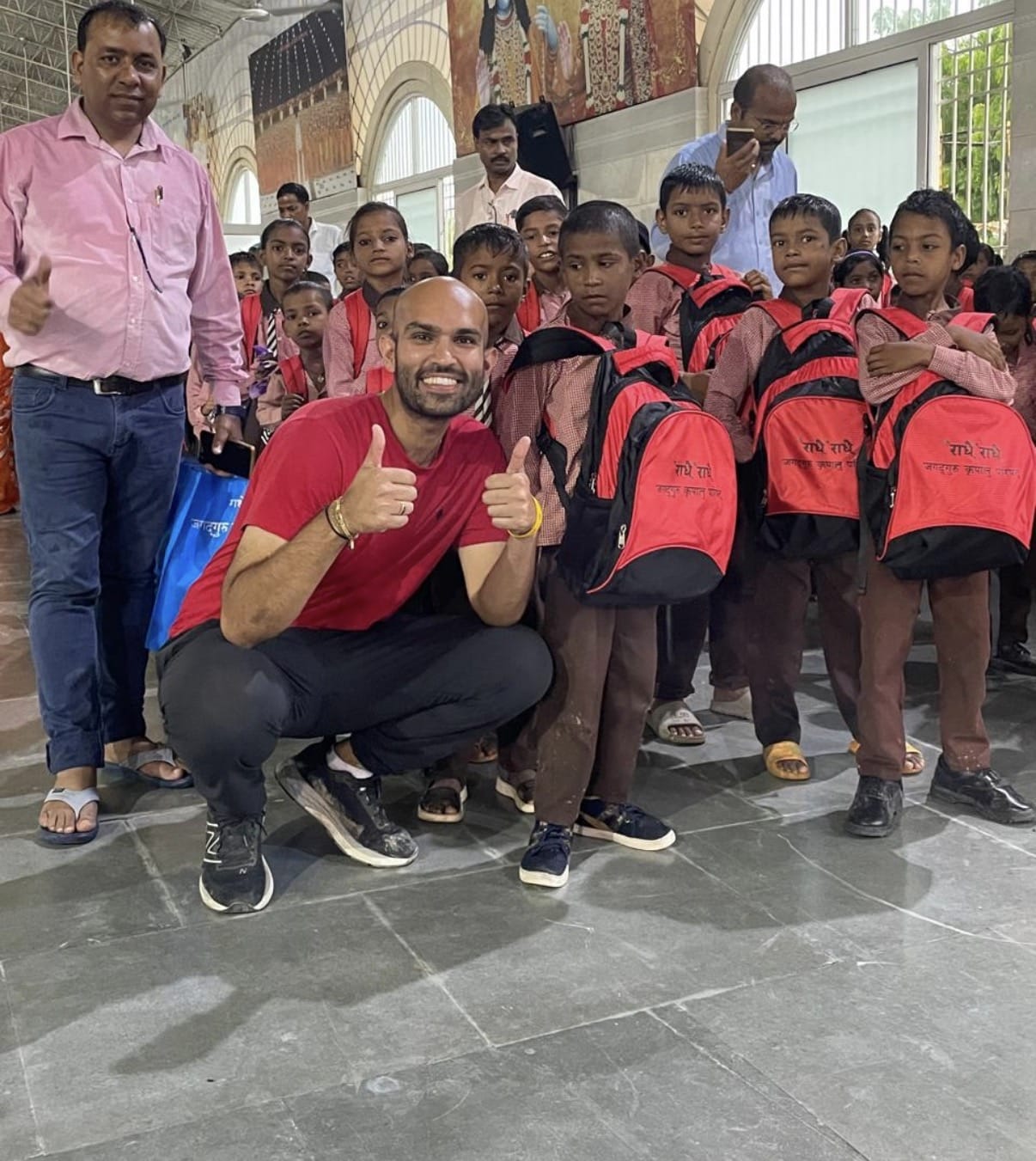 Smiling man with students wearing red backpacks|Ophthalmic surgeons performing eye surgery in operating room|Large beige public building with open plaza|Smiling person in purple shirt with colorful tiles