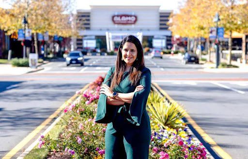 A woman standing in front of flowers and trees.