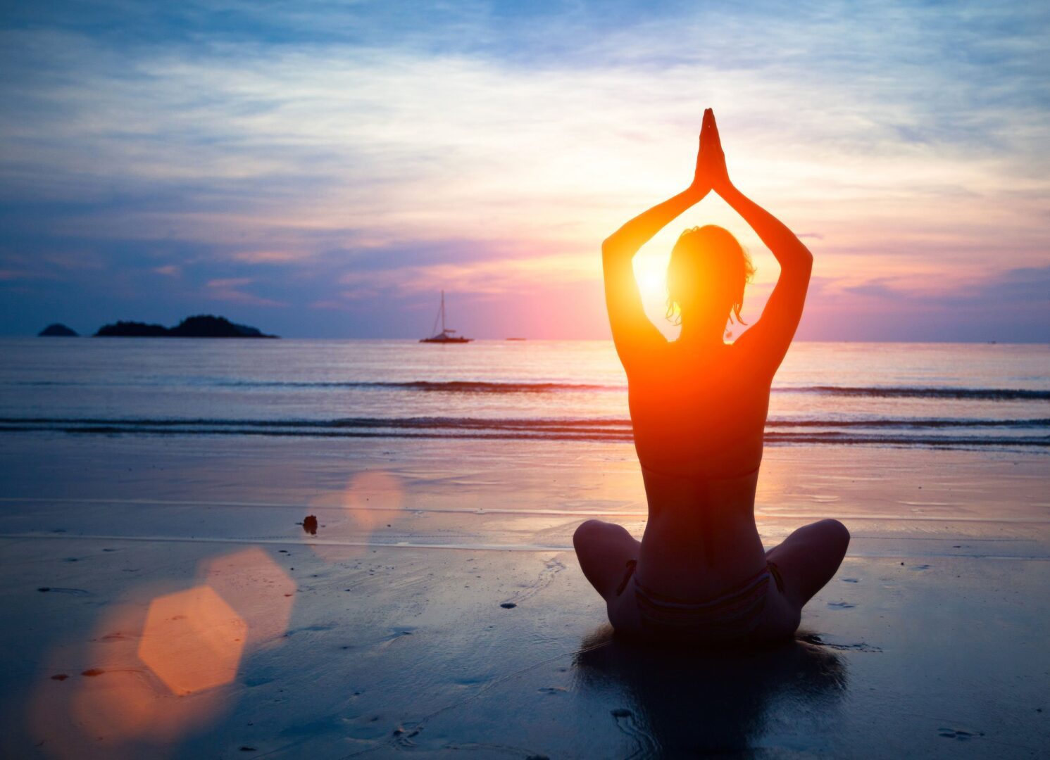 A person sitting on the beach doing yoga