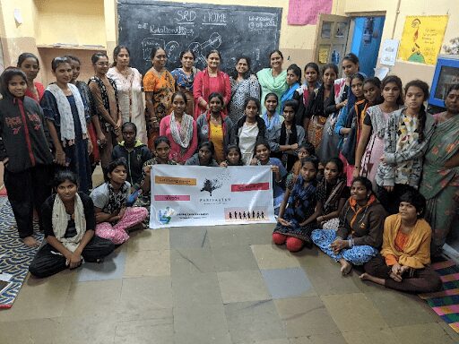 A group of women sitting in front of a chalkboard.|A group of women sitting in front of a chalkboard.|A group of children sitting on the floor in front of a chalkboard.|A group of people standing in front of two signs.