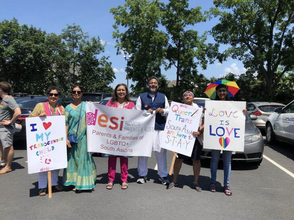 A group of people holding signs in front of a car.|A group of people holding signs in front of a car.|A group of people standing in the grass.