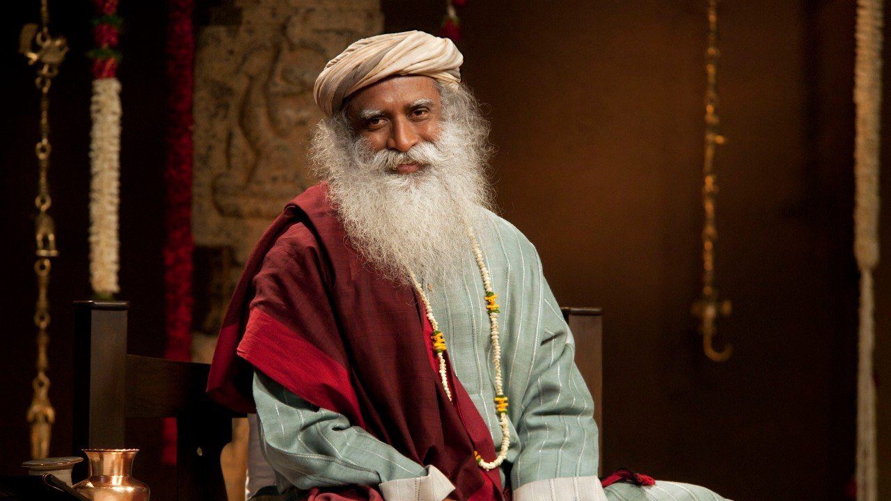 A man with long white hair and beard wearing a hat.|A poster of sadhguru with the date and time for the event.|A man with long white hair and beard wearing a hat.|A poster of sadhguru with the date and time for the event.
