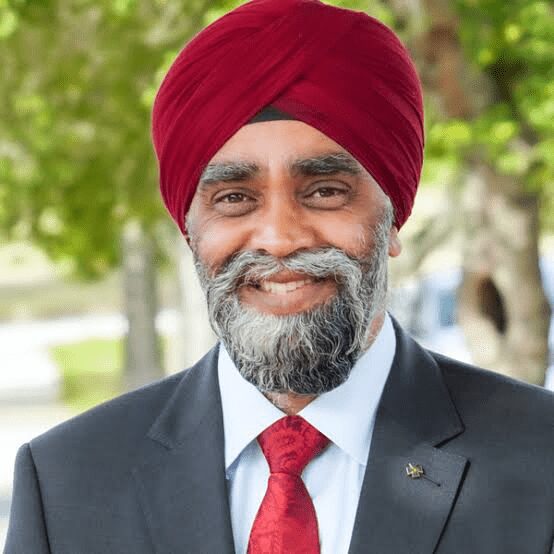 A man in a suit and turban smiling for the camera.