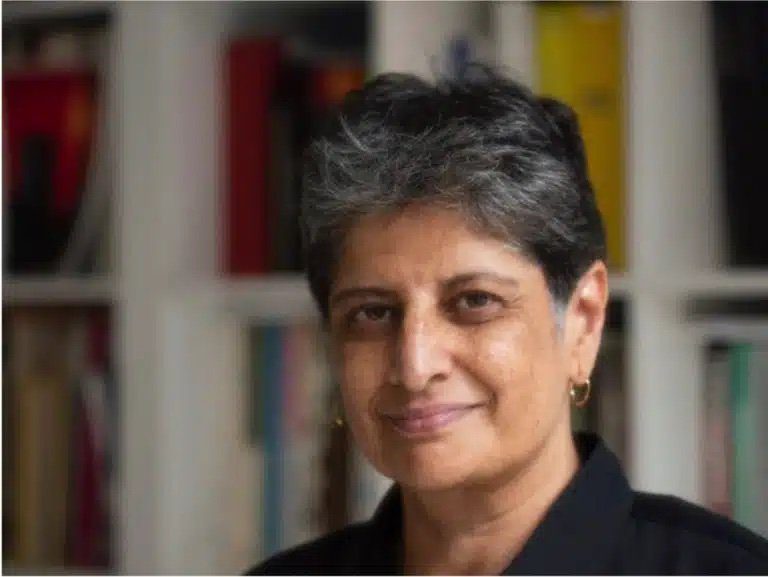 A woman with short hair is smiling for the camera.|A woman with long black hair wearing a black top.|A man with grey hair and wearing a brown jacket.|A man with pink hair and colorful makeup.|A man with grey hair and wearing a brown jacket.|A woman with long black hair wearing a red shirt.