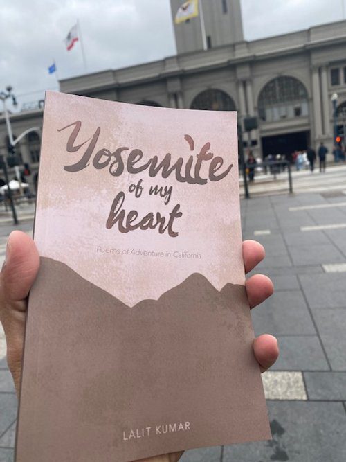 A hand holding up a book with the words " yosemite of my heart " written on it.|A man standing in front of some mountains