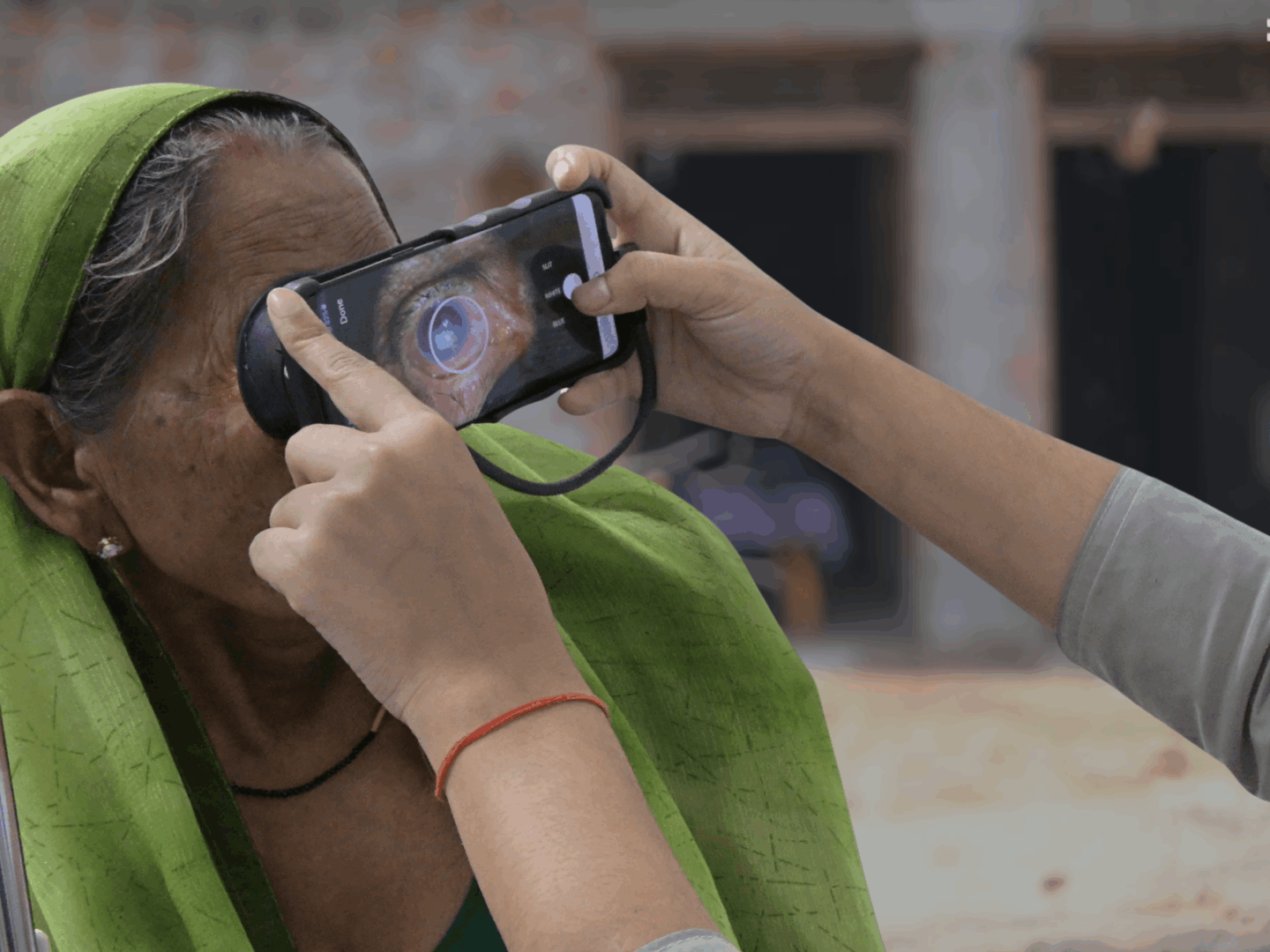 Smartphone eye exam on elderly woman|Two masked health workers holding mobile phones