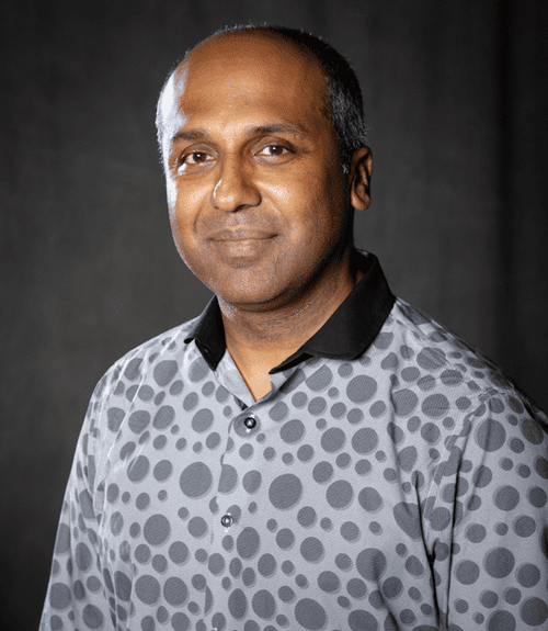 A man in a polka dot shirt poses for the camera.