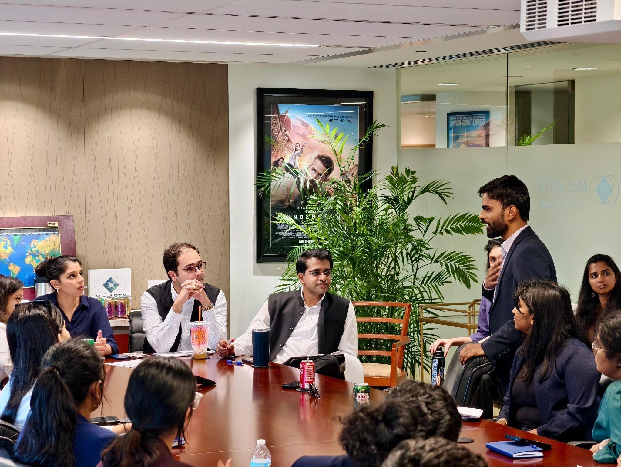 Business meeting with man presenting to team|Two people smiling, holding certificate at awards ceremony|Smiling man with beard wearing black shirt|Three people holding Apps Graduation 2025 plaque|Two people at awards ceremony holding certificate