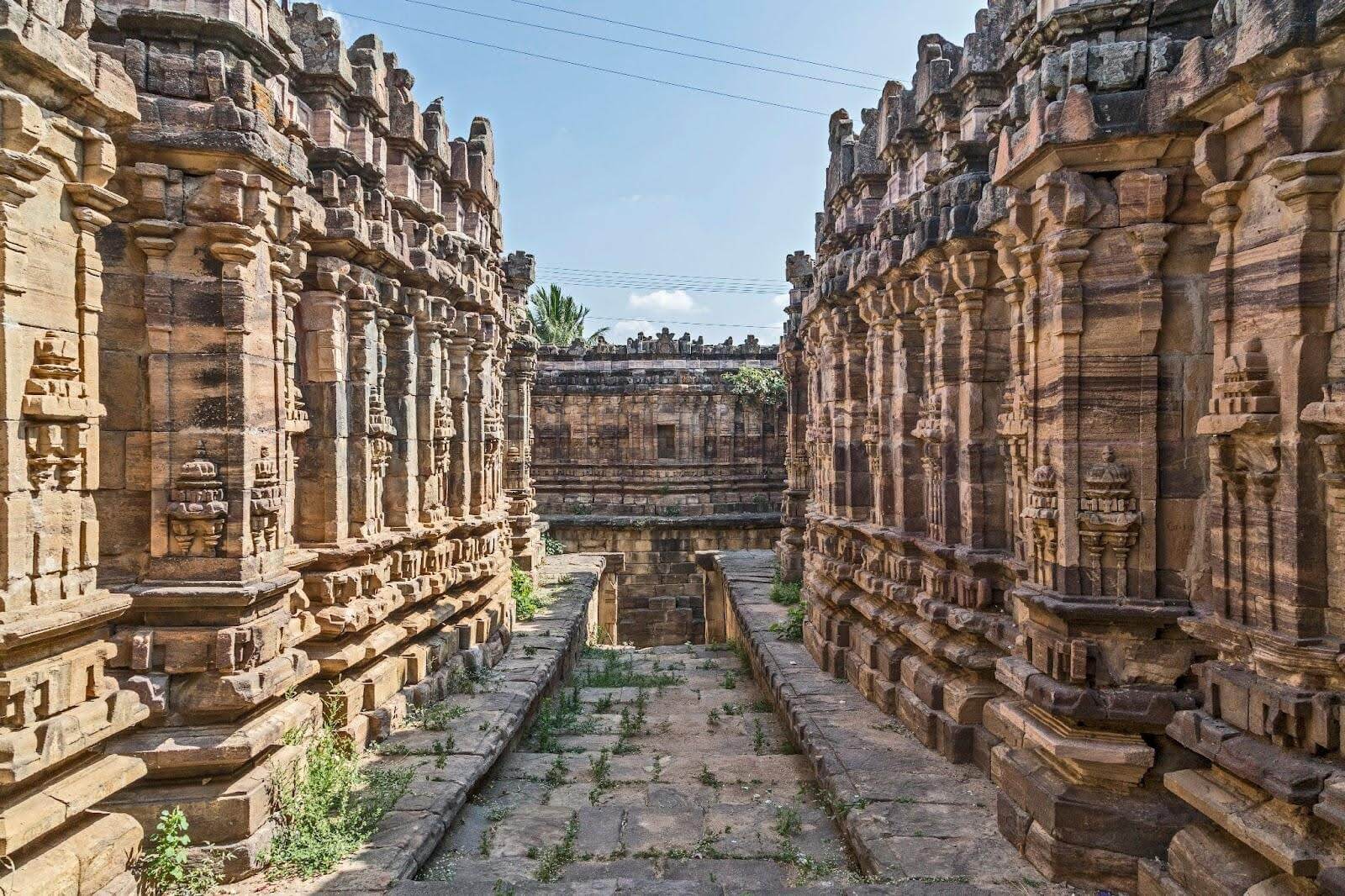 Ancient stone temple with intricate carvings.|Historic stone building with ornate architectural details.|Historic building surrounded by greenery.