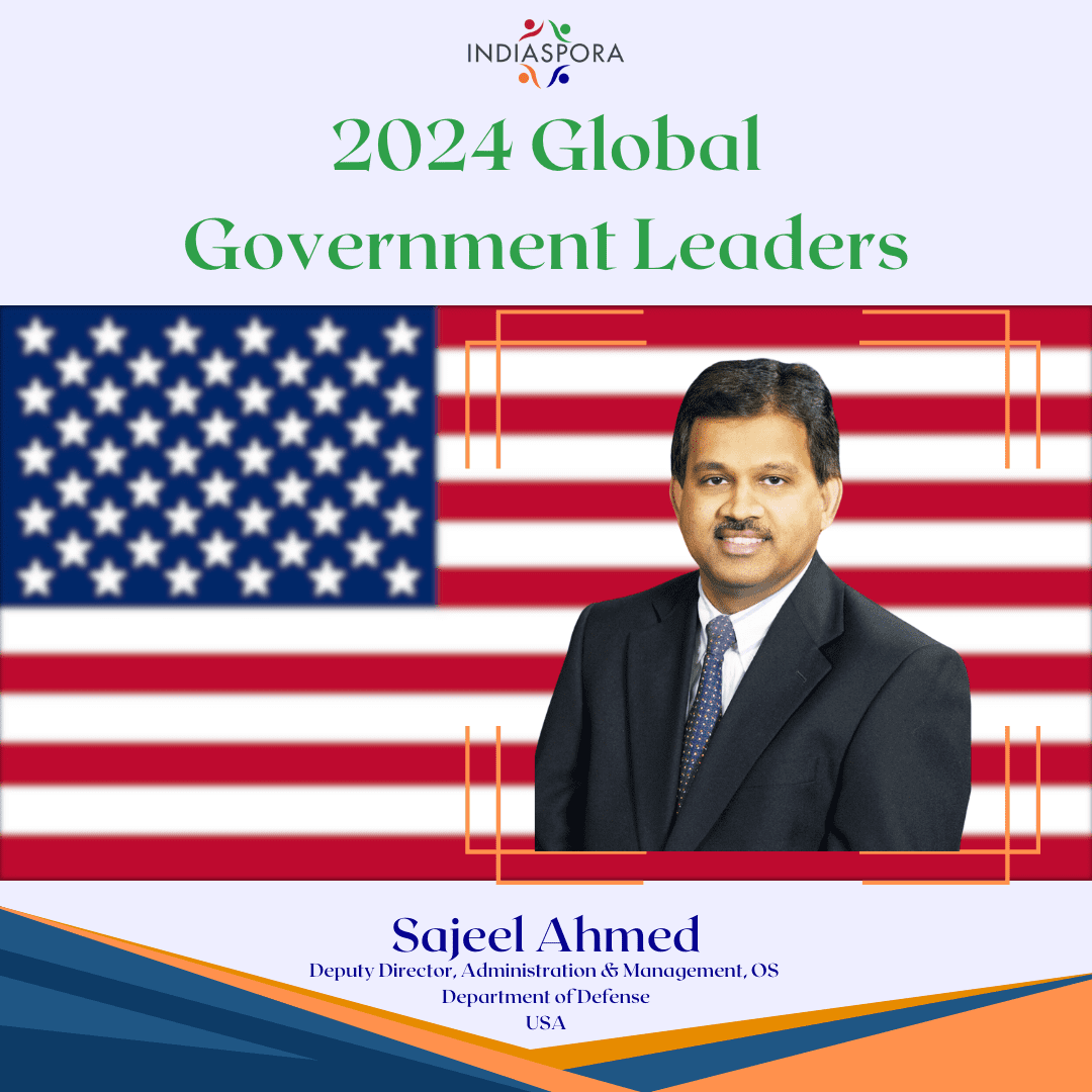 A picture of sujeel ahmed with the american flag.|A man in suit and tie next to an american flag.
