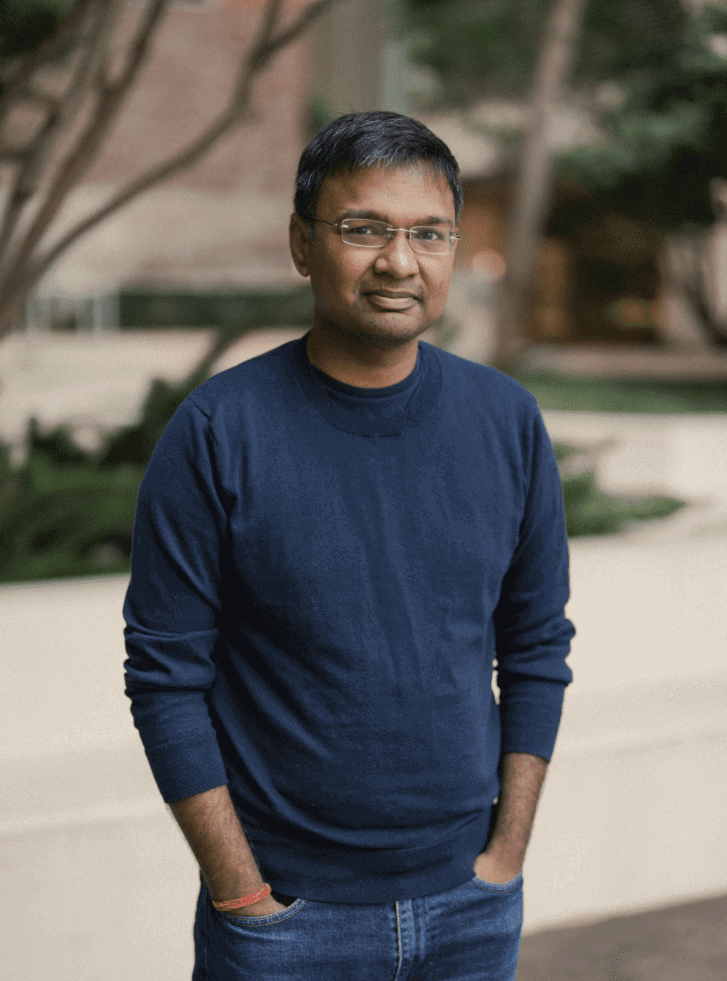 A man in blue shirt standing next to trees.