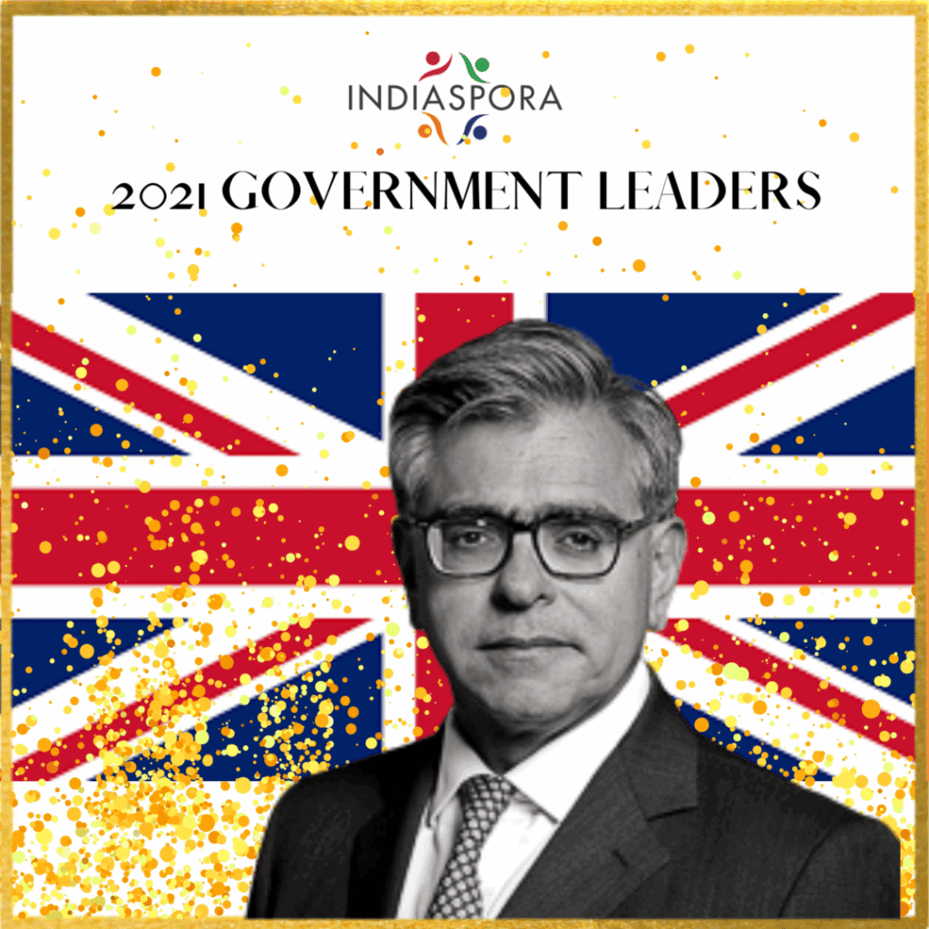 A man in glasses and suit standing next to the british flag.