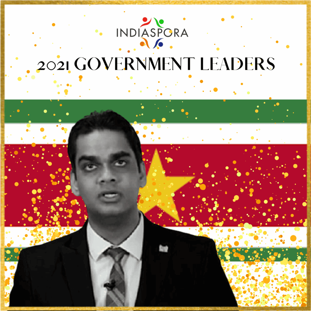 A man in suit and tie standing next to an image of the flag.