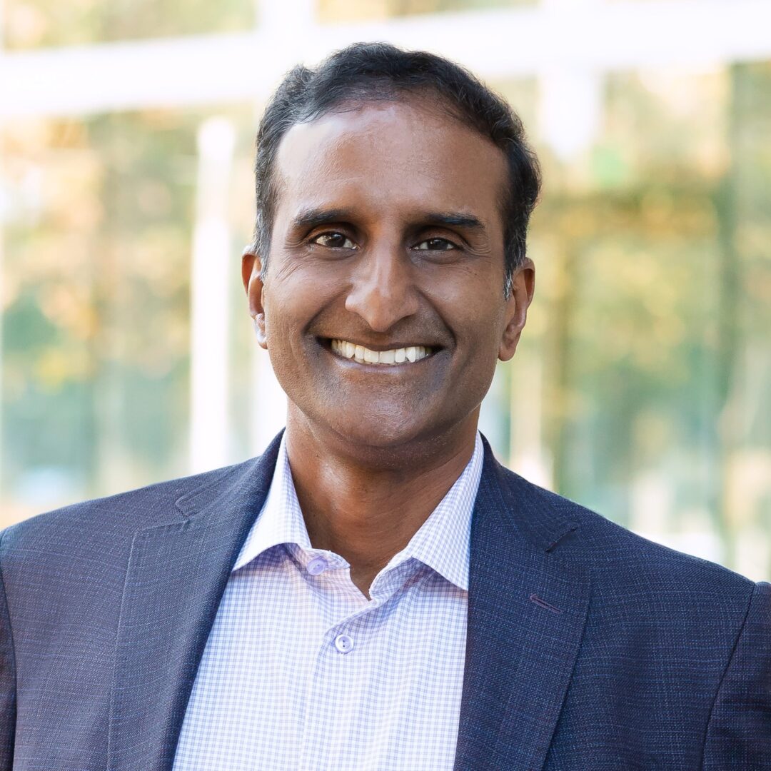 A man in a suit and tie smiling for the camera.