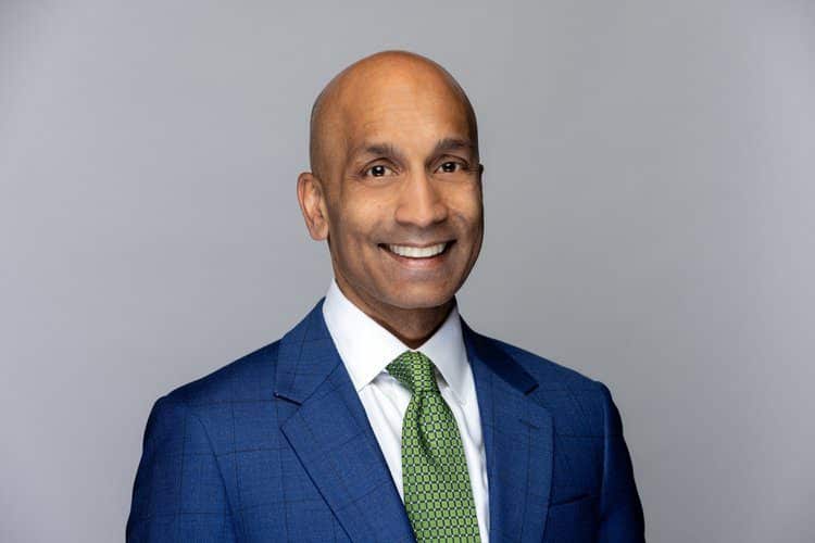 A man in a suit and tie smiling for the camera.