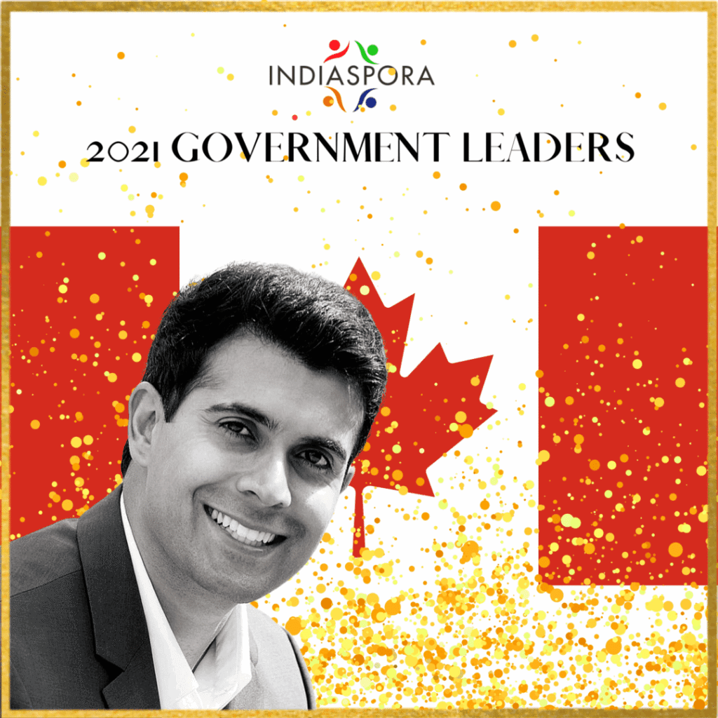 A man in a suit and tie next to the canadian flag.