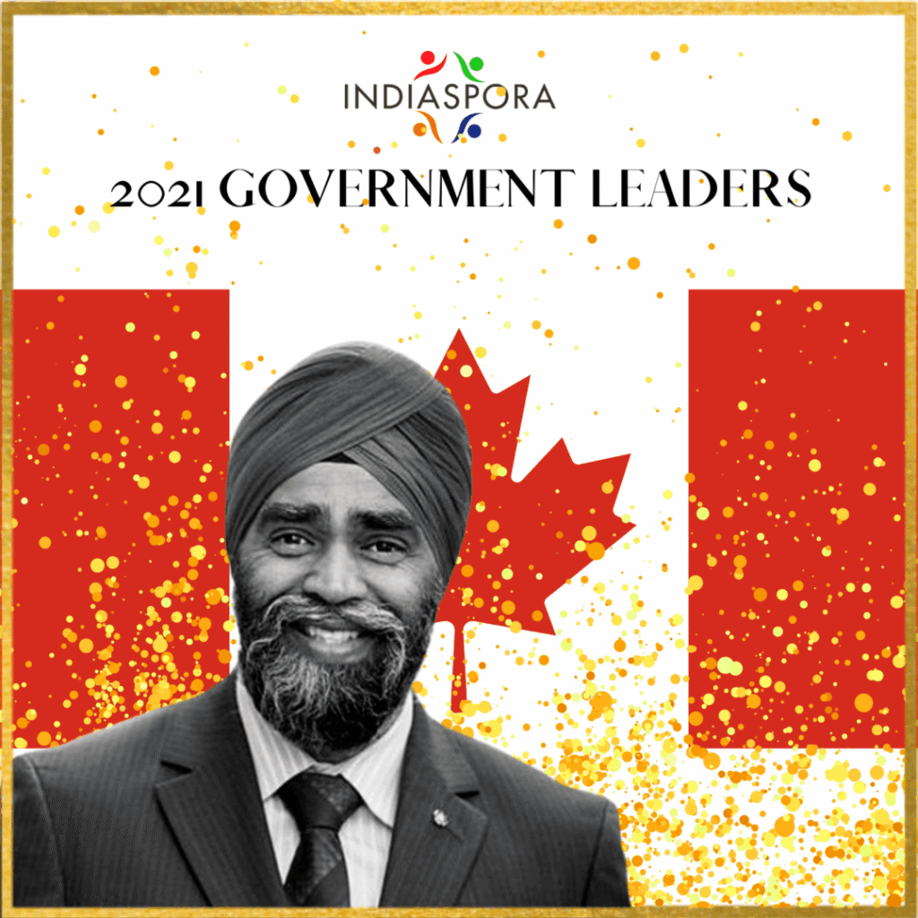 A man in a suit and tie standing next to canadian flag.