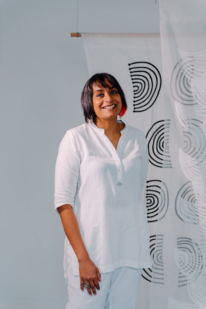 A woman standing in front of a curtain.